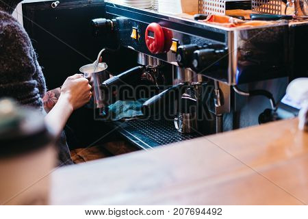 Professional coffee making machine with paper cups on top placed in the shop.