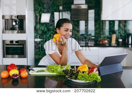 Young Woman Looking At Recipe In Laptop In Kitchen. Healthy Food - Vegetable Salad. Diet. Dieting Co