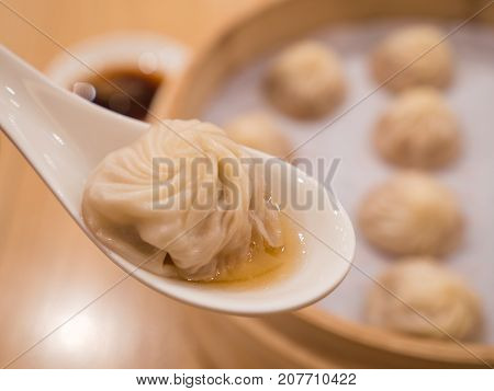 Closeup of Xiao Long Bao with soup in the spoon Streamed Pork Dumplings Taiwan food (Selective Focus)