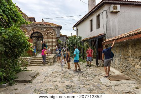NESEBAR BULGARIA - AUGUST 21 2017: A street with tourists in the old town and in the background of the Church of the Holy Archangels Michael and Gabriel (built between the 13th and 14th centuries).