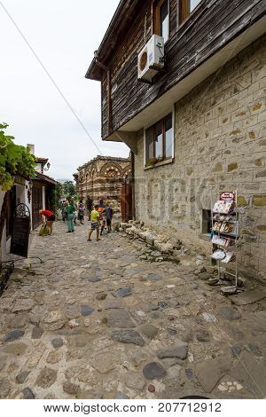 NESEBAR BULGARIA - AUGUST 21 2017: A street with tourists in the old town and in the background of the Church of the Holy Archangels Michael and Gabriel (built between the 13th and 14th centuries).