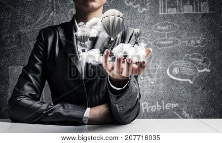 Closeup of business woman in suit presenting flying aerostate among clouds in her palm with business sketches on background. 3D rendering.