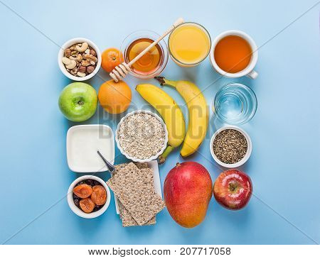 Healthy Food Fiber Source Breakfast Oatmeal Honey Fruits Apples Banana Mango Orange Juice Water Green Tea Nuts. Light Blue Tabletop. Modern Funky Square Flat Lay Top View.