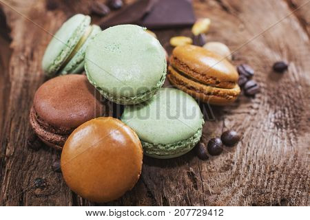 Macaroons with the flavors of coffee pistachio chocolate and raspberries presented on a piece of wood