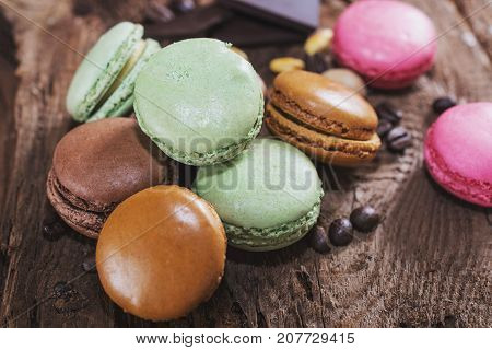 Macaroons with the flavors of coffee pistachio chocolate and raspberries presented on a piece of wood
