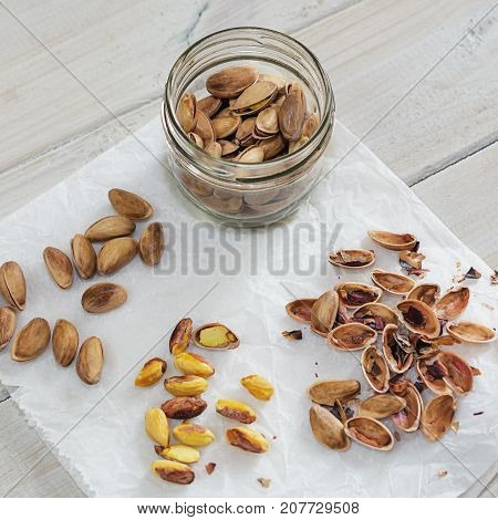 Peeled and unpeeled pistachio nuts presented on a white napkin