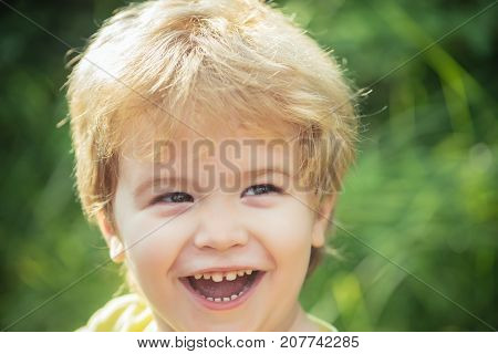 Happy boy smiling portrait. Child face with smile. Happy childhood. Joyful funny cheerful kid. Children background kindergarten. Beautiful child 3 years old. Portrait on green nature background
