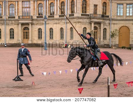 Gatchina St. Petersburg Russia - September 30 2017: Horse show of Cossacks on the parade ground of the Gatchina Palace. A Cossack on a horse jumps with a spear.