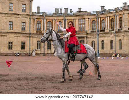 Gatchina St. Petersburg Russia - September 30 2017: Horse show of Cossacks on the parade ground of the Gatchina Palace. A Cossack girl on a white horse welcomes the audience.