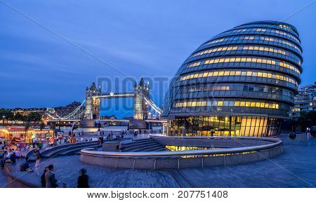 LONDON UK - AUG 1: London City Hall and Tower Bridge on August 1, 2017 in London UK. The City Hall has an unusual bulbous shape was designed by Norman Foster and opened in July 2002.
