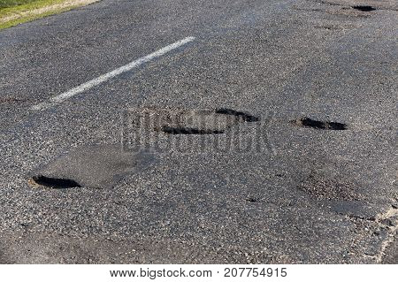 A Large Number Of Holes In The Asphalt Road. Poor Quality Of Construction And Infrastructure In The 