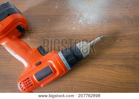 Drill machine on wooden table with a lot of dust.