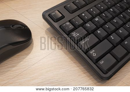 Close up on the keyboard and wireless mouse on wooden table.
