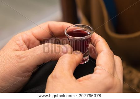 A lady's hands hold a red wine cup in Holy Communion.