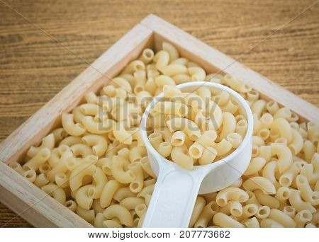 Food and Cuisine Uncooked and Dried Elbow Macaroni or Gomiti Pasta in Plastic Measuring Cup.
