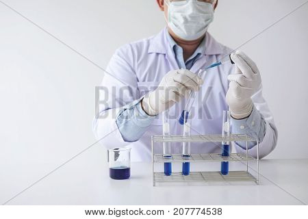 Scientist or medical in lab coat holding test tube with reagent with drop of color liquid over glass Biochemistry laboratory research.