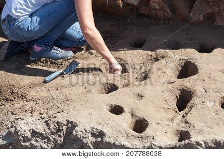 Female archaeologist digging holes at archaeological site. Archeology.