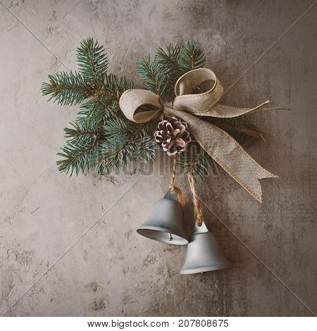branch Christmas tree with bells shot and bow on a background of a concrete wall