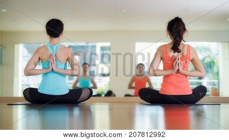 Yoga training in lotus action with back side asian lady in fitness center