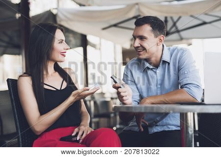 A reporter at work. The journalist writes down the answers of the girl to the dictophone. At the table there is a cheerful conversation