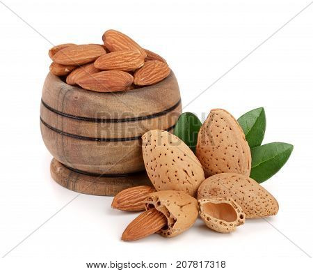 Almonds in a wooden bowl with leaves isolated on white background.
