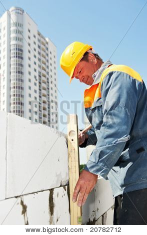 trabalhador da construção civil pedreiro controlo qualidade de alvenaria com medição de nível