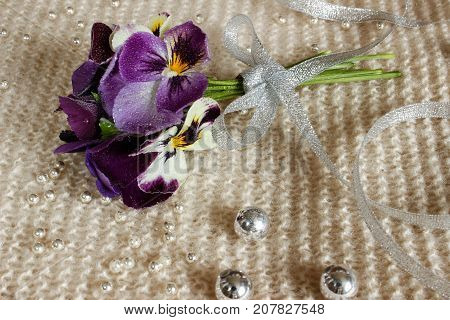 Still life with a pansy a bouquet of flowers tied with ribbon and strewn with beads