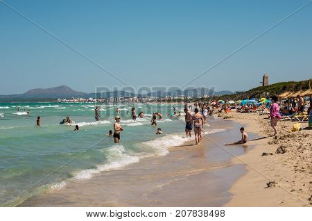 Can Picafort, Majorca, Balearic islands, July 2017: Tourists in Playa de Muro beach with Can Picafort town and mountains in background northern part of the island