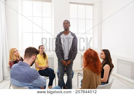 African american man patient standing in circle and telling his problems to therapy group, copy space