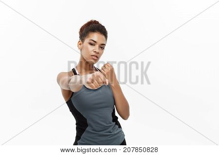 Healthy and Fitness concept - portrait of African American woman punching in air with confident face. Isolated on white background.