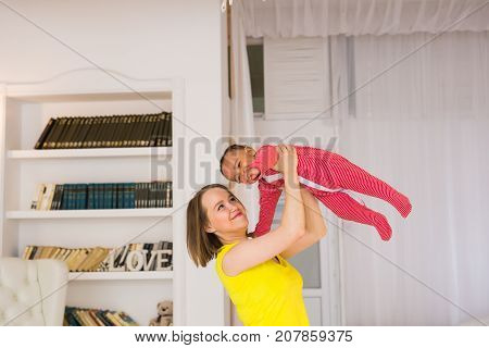 happy family. Mother throws up baby, playing at home.