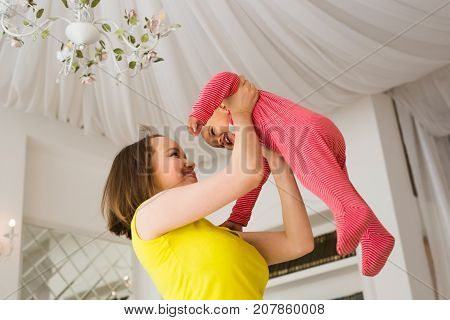 happy family. Mother throws up baby, playing at home.