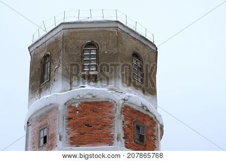 The top is an old destroyed brick water tower in winter covered with snow.