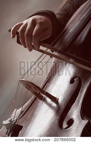 Close-up of a person's hand playing classical music on a violoncello. Musical concept