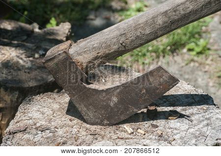 Old used weathered wooden axes stuck on wooden log for splitting wood into farmyard