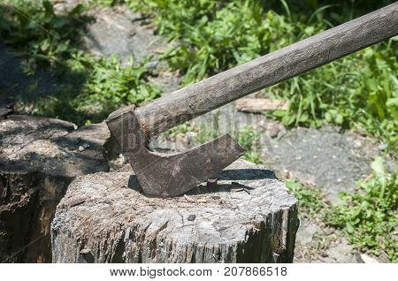 Old used weathered wooden axes stuck on wooden log for splitting wood into farmyard