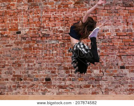Dance is freedom. Happiness in moving. Lightness in life, sporty teenage girl on brick wall background with free space. Hip hop lifestyle, dancing young female, breakdance concept