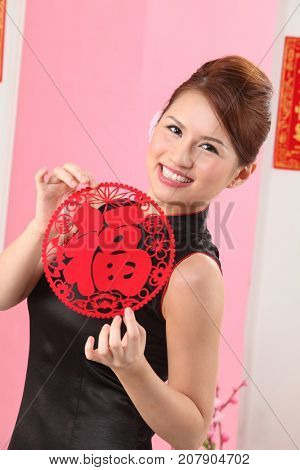 Young woman celebrating Chinese New Year holding paper cutting