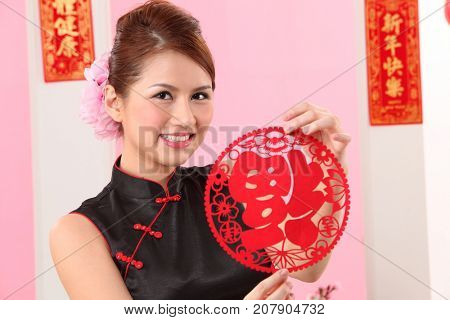 Young woman celebrating Chinese New Year holding paper cutting