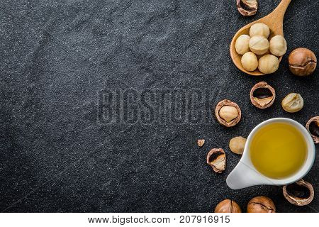 The Macadamia Nut Oil and peeled macadamia nut  on black stone , ﻿use for Healthy Skin and Hair and Natural Healing Oil Treatment , overhead and top view