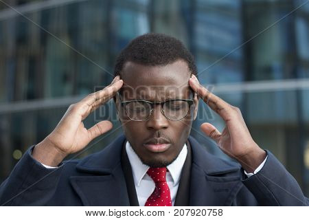 Urban Portrait Of Stressed Dark-skinned Guy Wearing Formal Clothes Touching Temples With Fingers, Ey