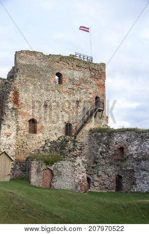 The ruins of the Livonia Order Castle was built in the middle of the 15th century. Bauska Latvia in autumn. Latvian flag on the top of the tower