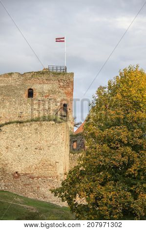 The ruins of the Livonia Order Castle was built in the middle of the 15th century. Bauska Latvia in autumn. Latvian flag on the top of the tower