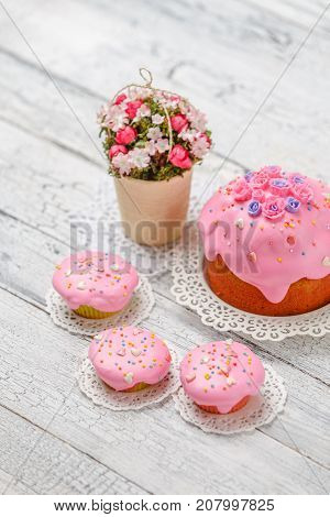 Traditional Easter cake with decorations and cupcakes on wooden table
