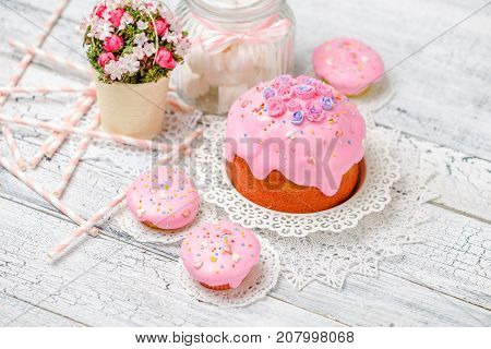 Traditional Easter cake with decorations and cupcakes on wooden table