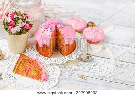 Traditional Easter cake with decorations and cupcakes on wooden table