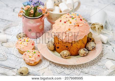 Traditional Easter cake with decorations and cupcakes on wooden table