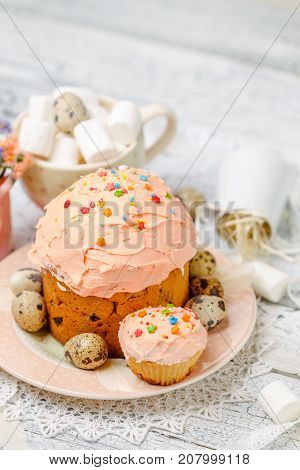 Traditional Easter cake with decorations and cupcakes on wooden table