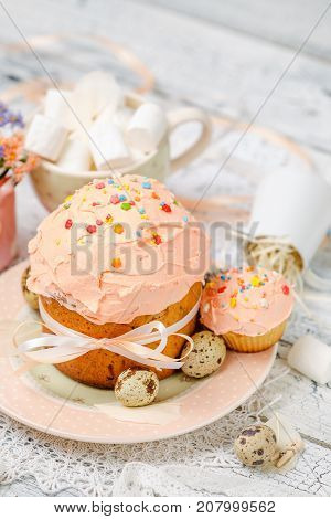 Traditional Easter cake with decorations and cupcakes on wooden table