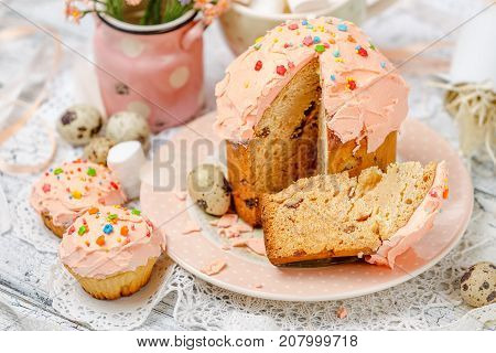 Traditional Easter cake with decorations and cupcakes on wooden table